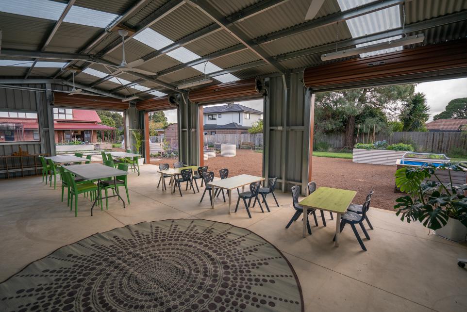 Outdoor shed with roller doors open to the garden and small tables and chairs