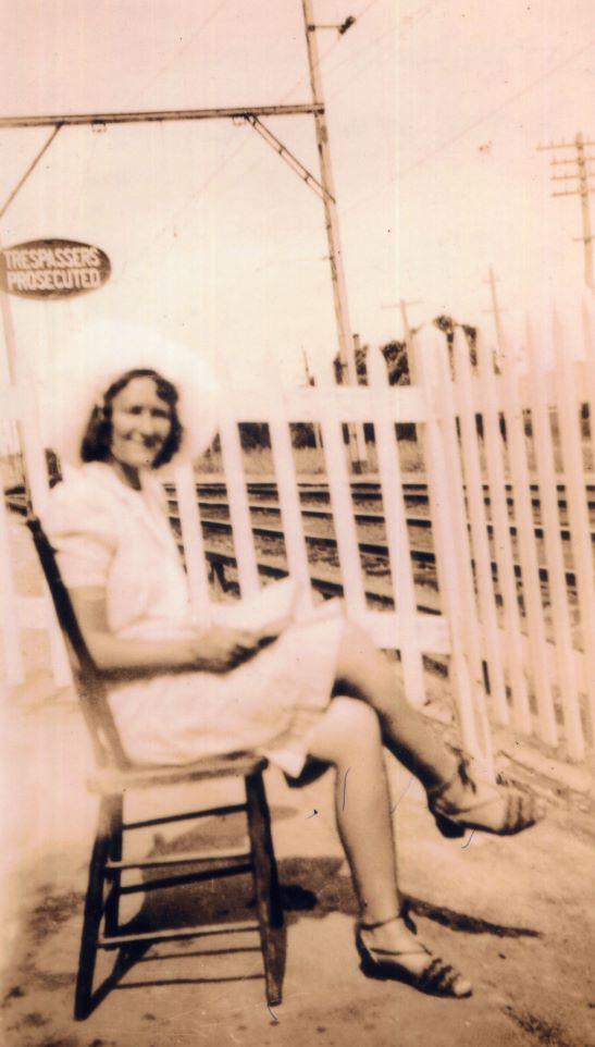 Woman seated by the rail station gates.