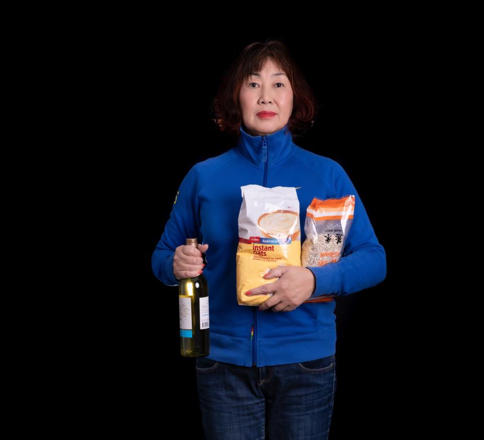 Portrait of a Chinese lady holding a bottle of wine and bag of instant oats