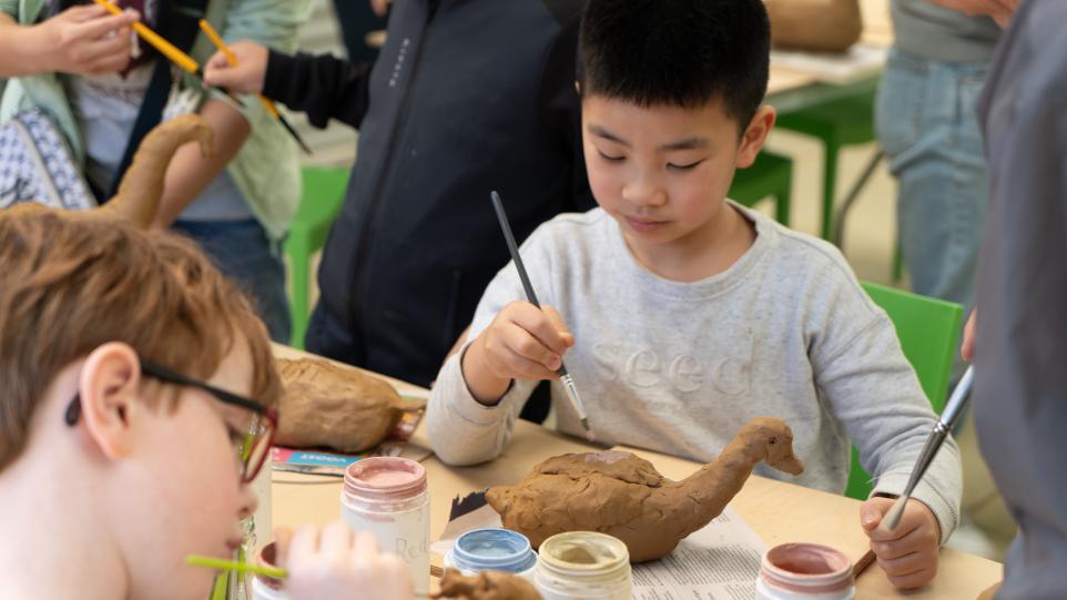 Child painting clay duck in Strathdon House Packing Shed