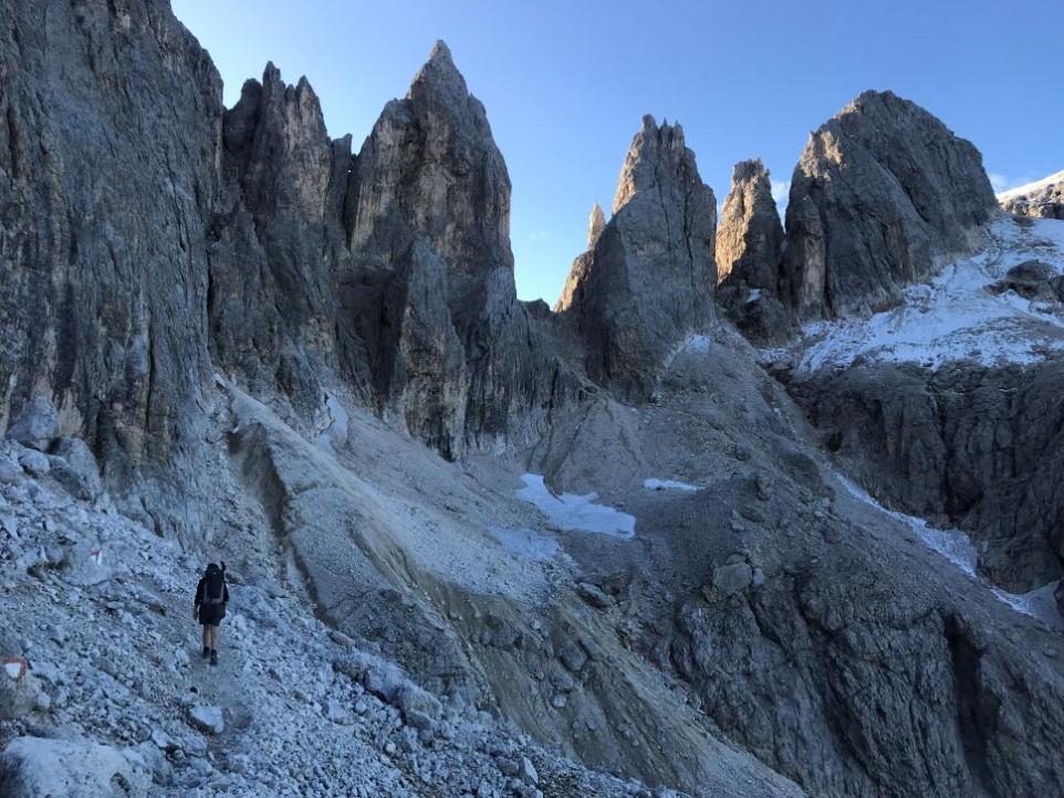 Photograph of a landscape with dolomites and small figure climbing.