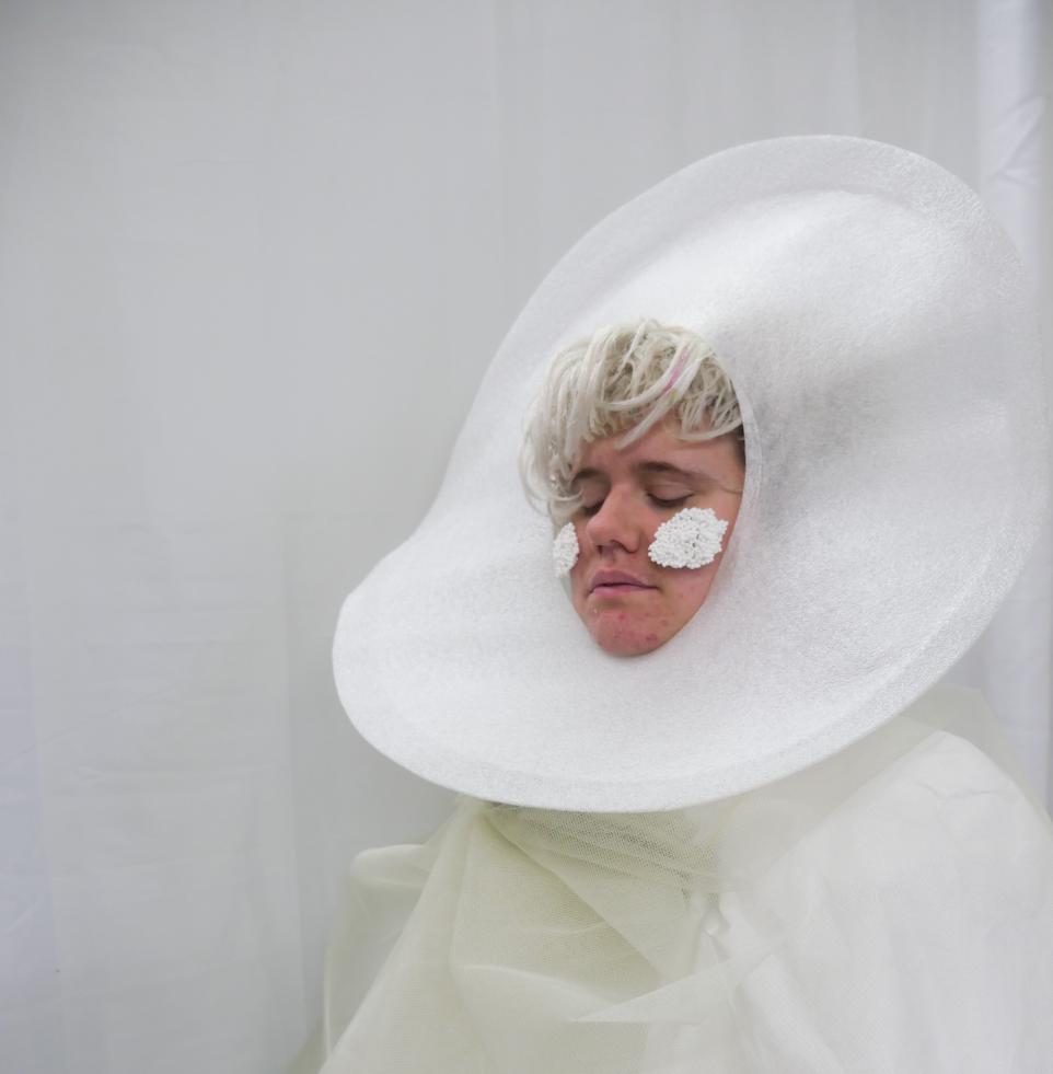 Photograph of a girl dressed in white foam headdress, clouds on her cheeks 