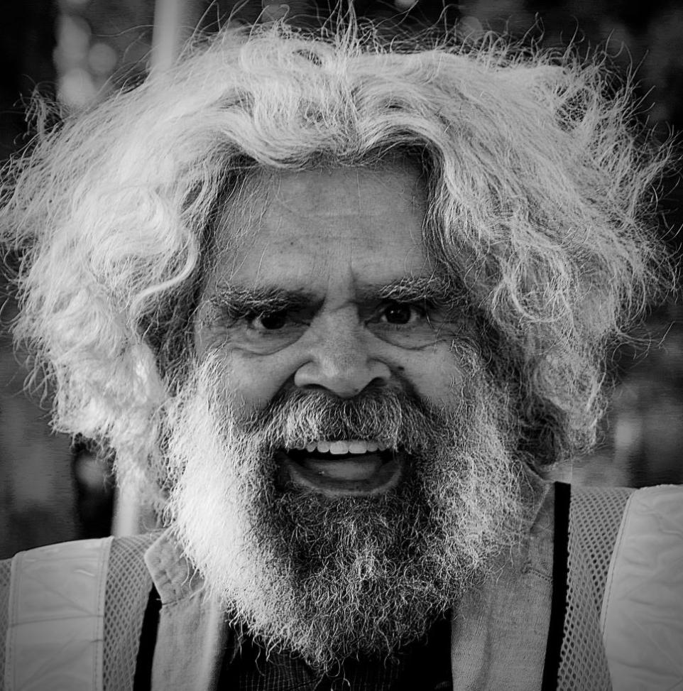 Black and white close-up photograph of smiling man with white hair 