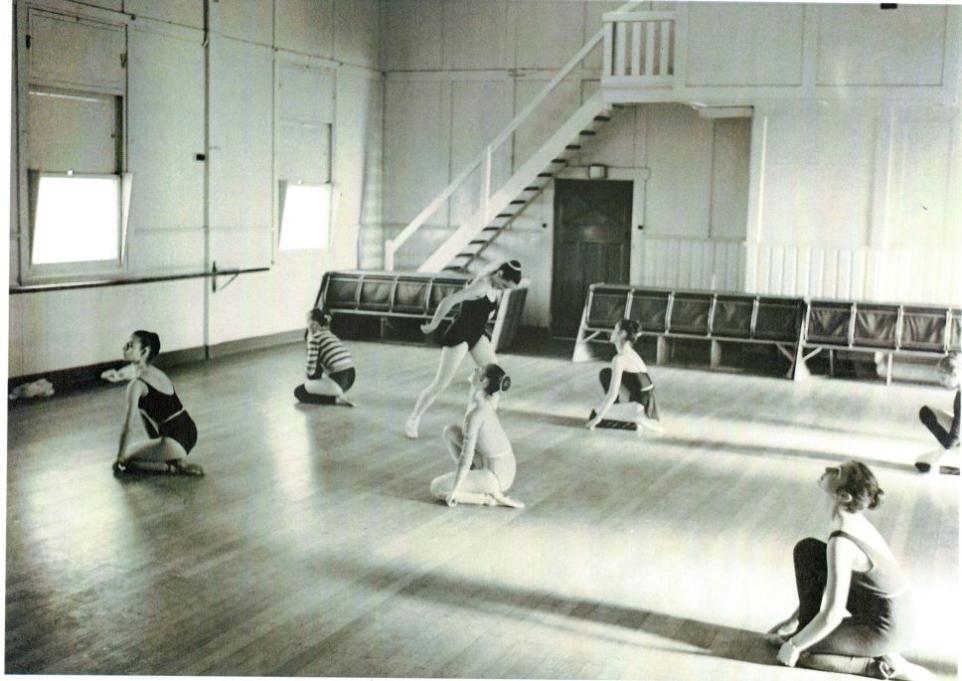 Black and white photo of girls rehearsing ballet in a hall.