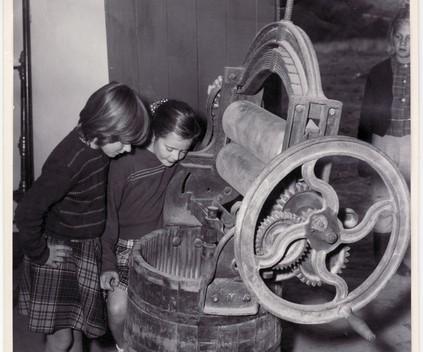 Black and white photo depicting children looking into an early washing machine