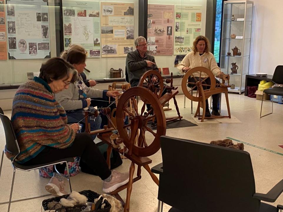 Group sitting together using spinning wheels.