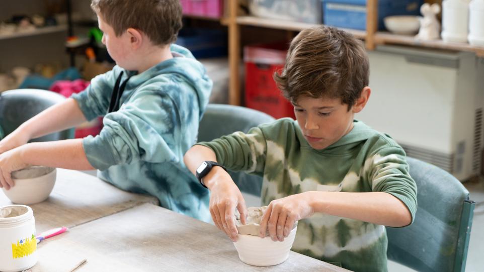 young boy hand building with clay in ceramic studio