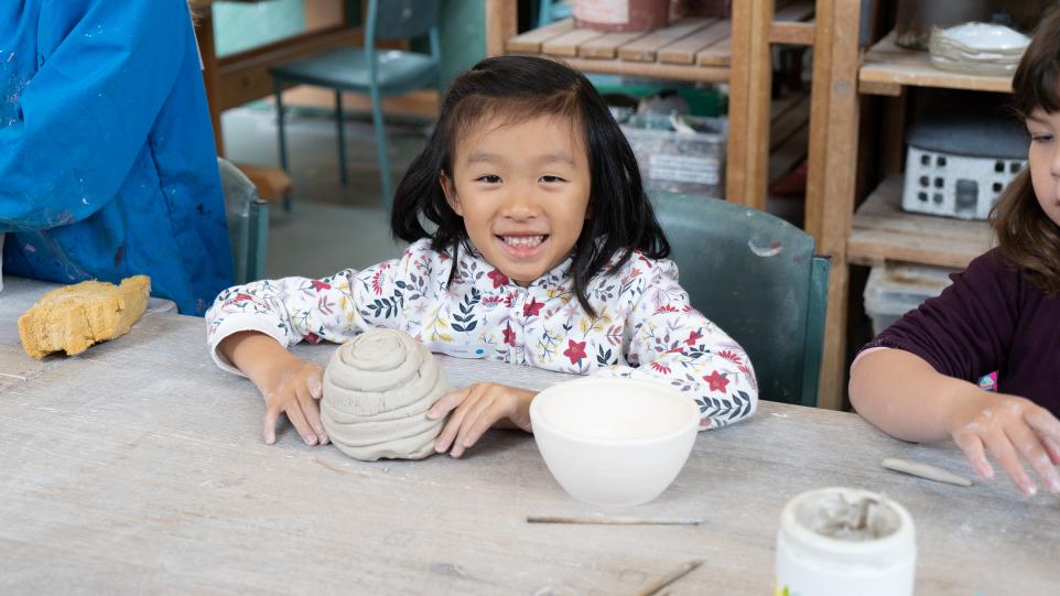 young child hand building with clay in ceramic studio