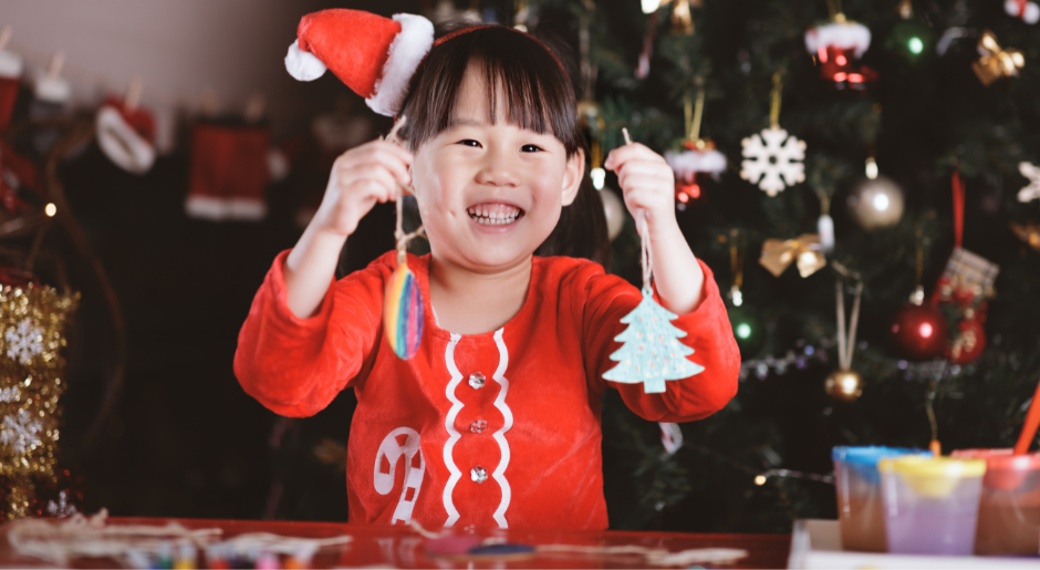 Girl in festive outfit holding up Christmas decorations