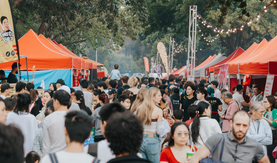 Large crowd of people walking through a street festival