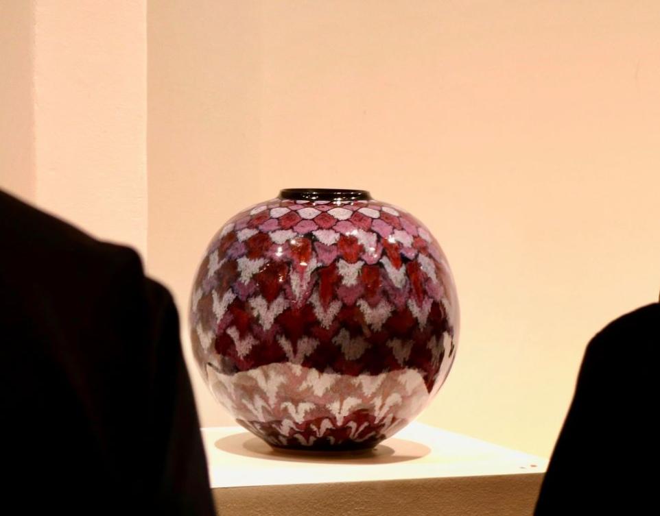 Ceramic jar with purple diamond pattern on display in a gallery