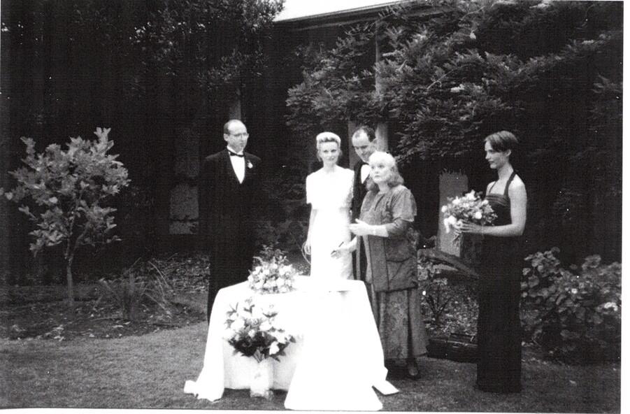 Black and white photo of wedding ceremony in front of cottage