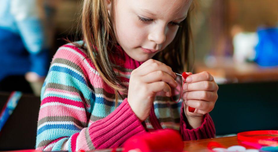 young child threading a needle 