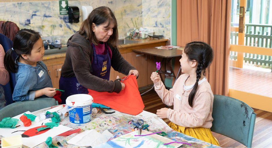 children in craft workshop with tutor cutting fabric 