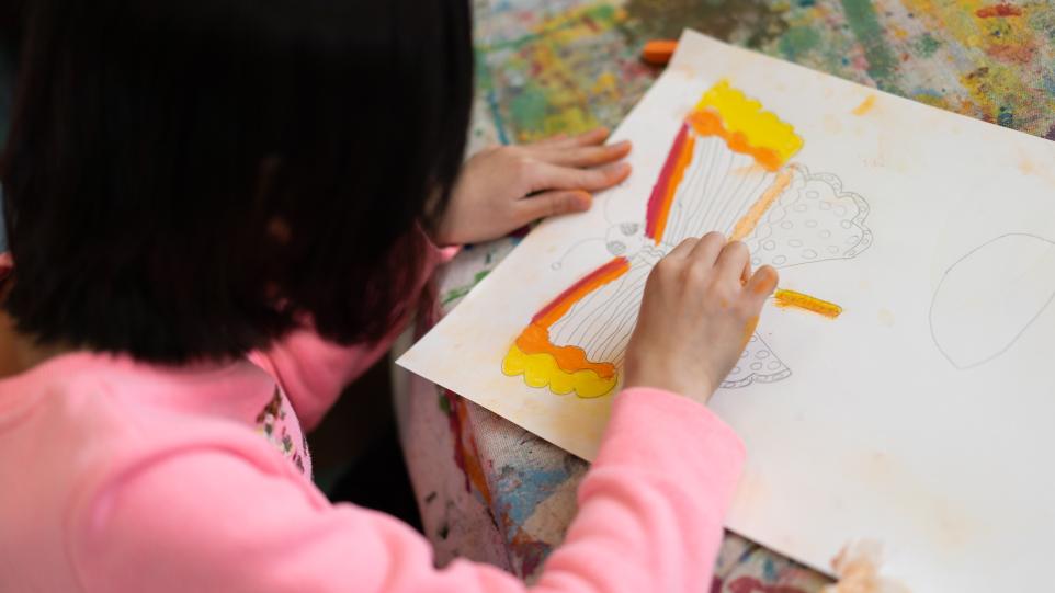 young child drawing a butterfly with pastels 