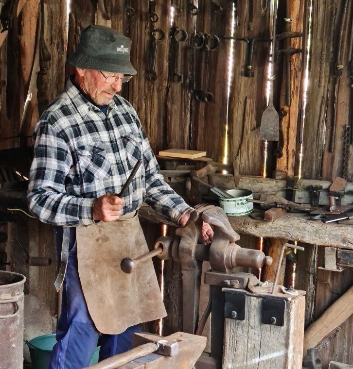 Photo of a blacksmith working in a barn.