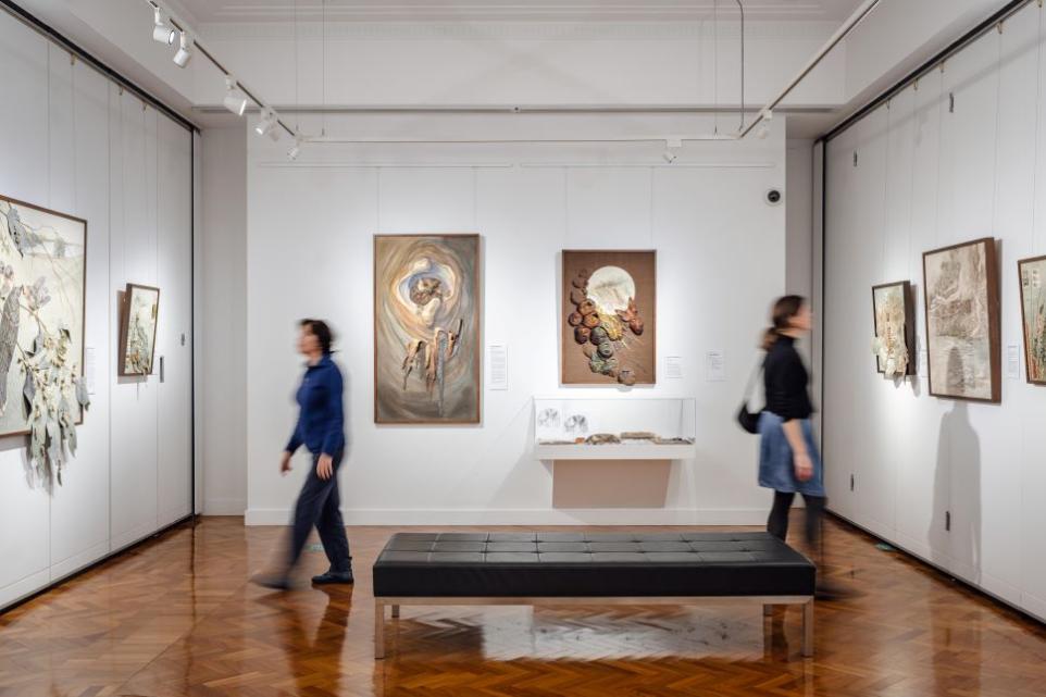 View of a gallery with two visitors looking at textile art.
