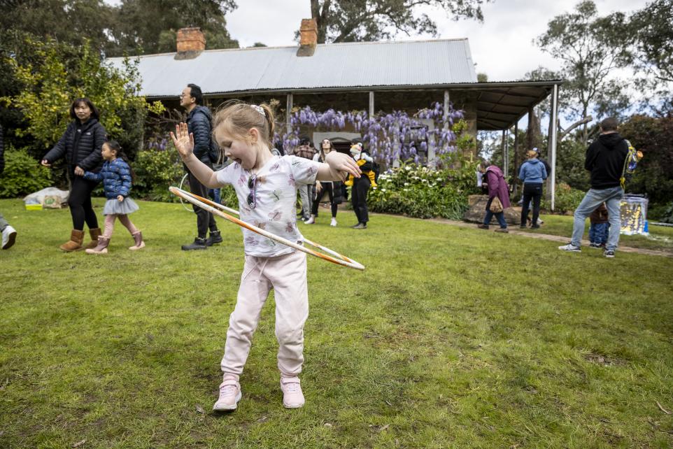 A photograph of a young girl playing with a hula hoop outside Schwerkolt Cottage