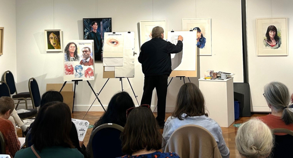 Artist doing painting demonstration in gallery for audience