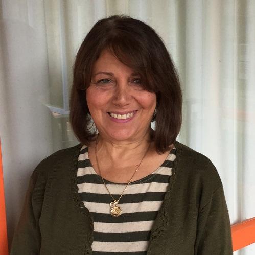 A lady with short brown hair, a white and black stripy shirt smiling at the camera