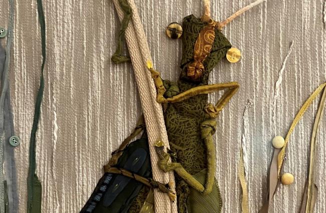 An embroidered cricket on a silver fabric background