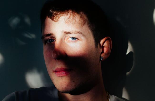 Portrait of a young man looking at the camera though shadows.