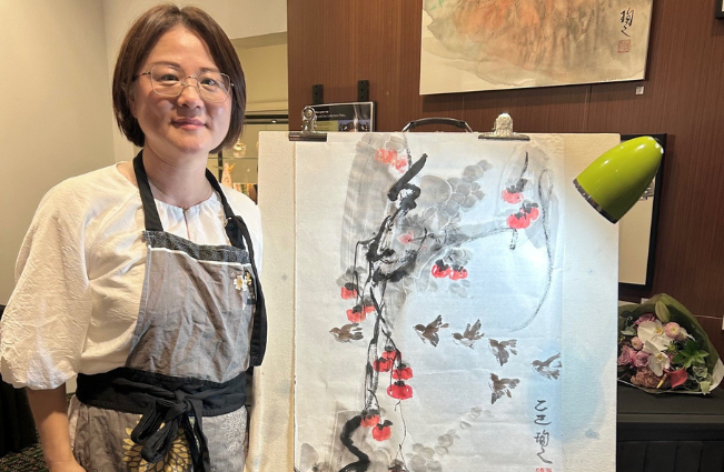 Artist Echo Wu standing beside her artwork. 