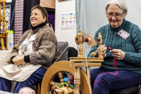 Two women spinning wool with a wheel.