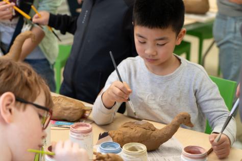 Child painting clay duck in Strathdon House Packing Shed