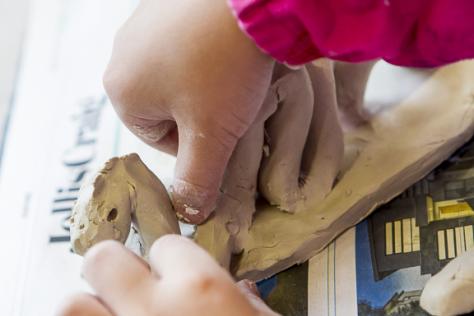 Child hand building with clay