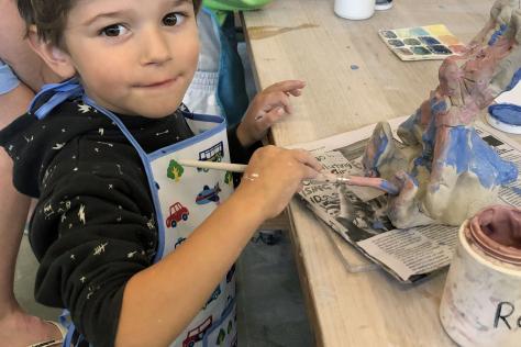 small child paining clay bunny