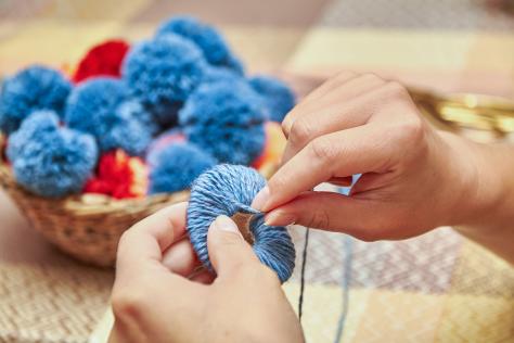 hands making pompoms with wool