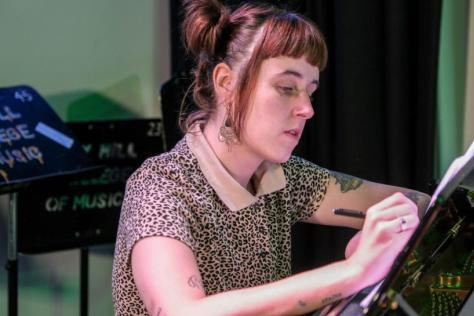 Young woman in leopard print top writing in a music studio.