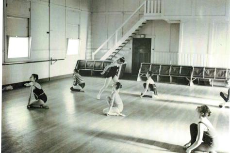 Black and white photo of girls rehearsing ballet in a hall.