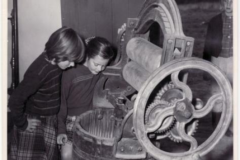 Black and white photo depicting children looking into an early washing machine