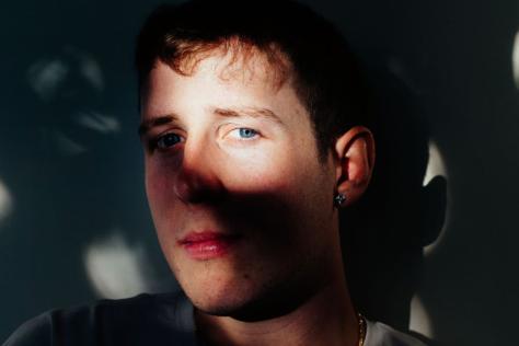 Portrait of a young man looking at the camera though shadows.