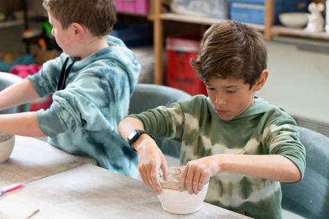 young boy hand building with clay in ceramic studio