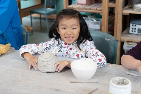 young child hand building with clay in ceramic studio