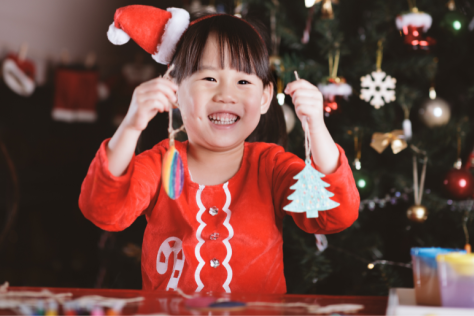 Girl in festive outfit holding up Christmas decorations