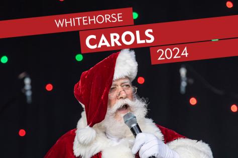 Person dressed as Santa singing into a microphone on a stage