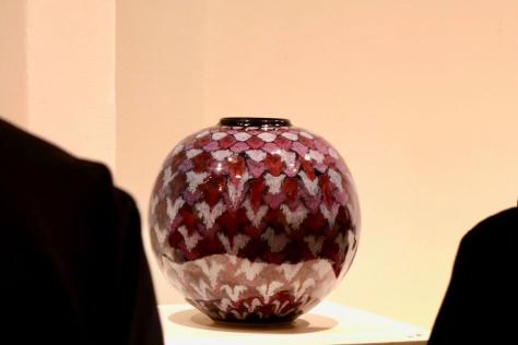 Ceramic jar with purple diamond pattern on display in a gallery