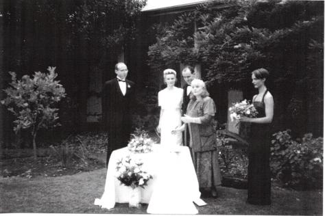 Black and white photo of wedding ceremony in front of cottage