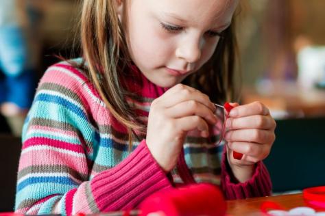 young child threading a needle 