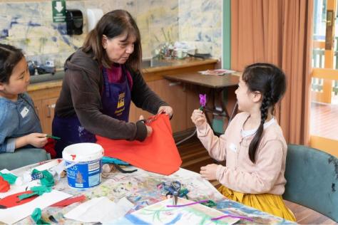 children in craft workshop with tutor cutting fabric 