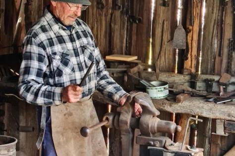 Photo of a blacksmith working in a barn.