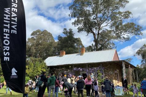 Crowd of visitors outside a stone cottage, bubbles blowing.