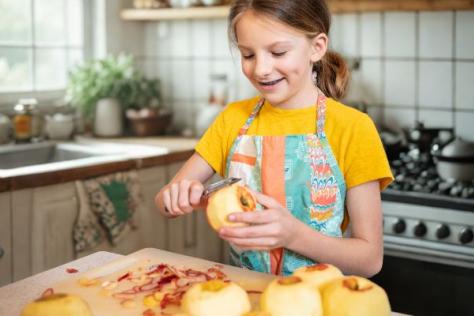 Child peeling apple in kids cooking workshop 
