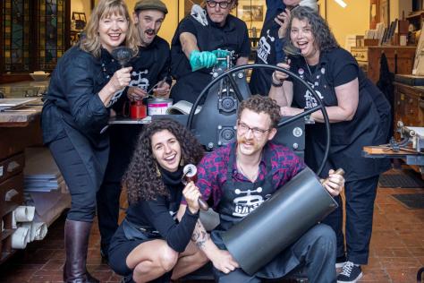 Group of people posing for the camera with printmaking equipment