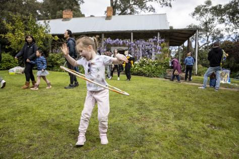 A photograph of a young girl playing with a hula hoop outside Schwerkolt Cottage