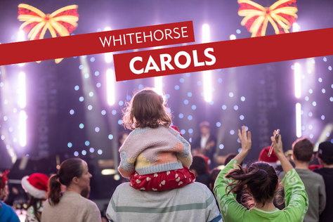 young girl sitting on parents shoulder watching outdoor stage